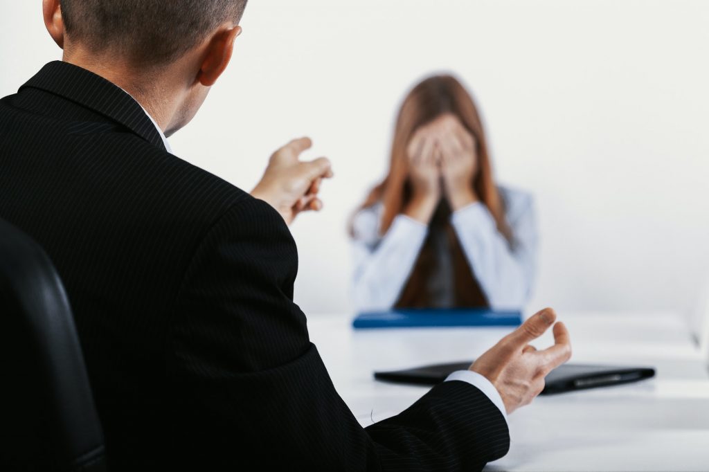 Depressed young woman during a conversation with the boss who points out her mistakes