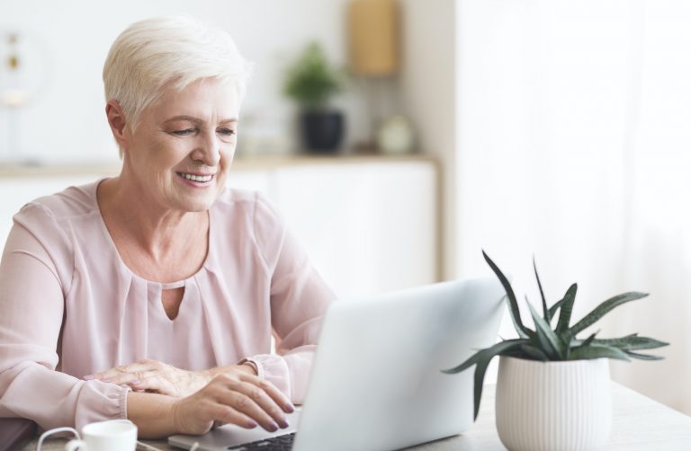 Smiling senior business lady looking at laptop