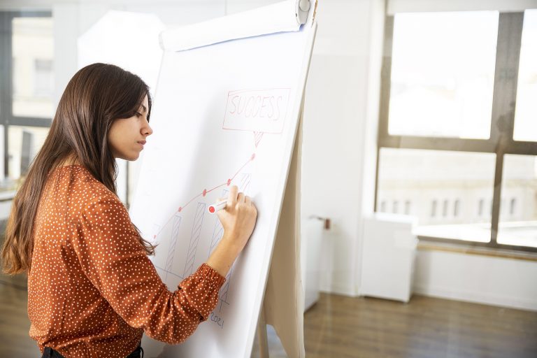 Woman entrepreneur writing on whiteboard in office